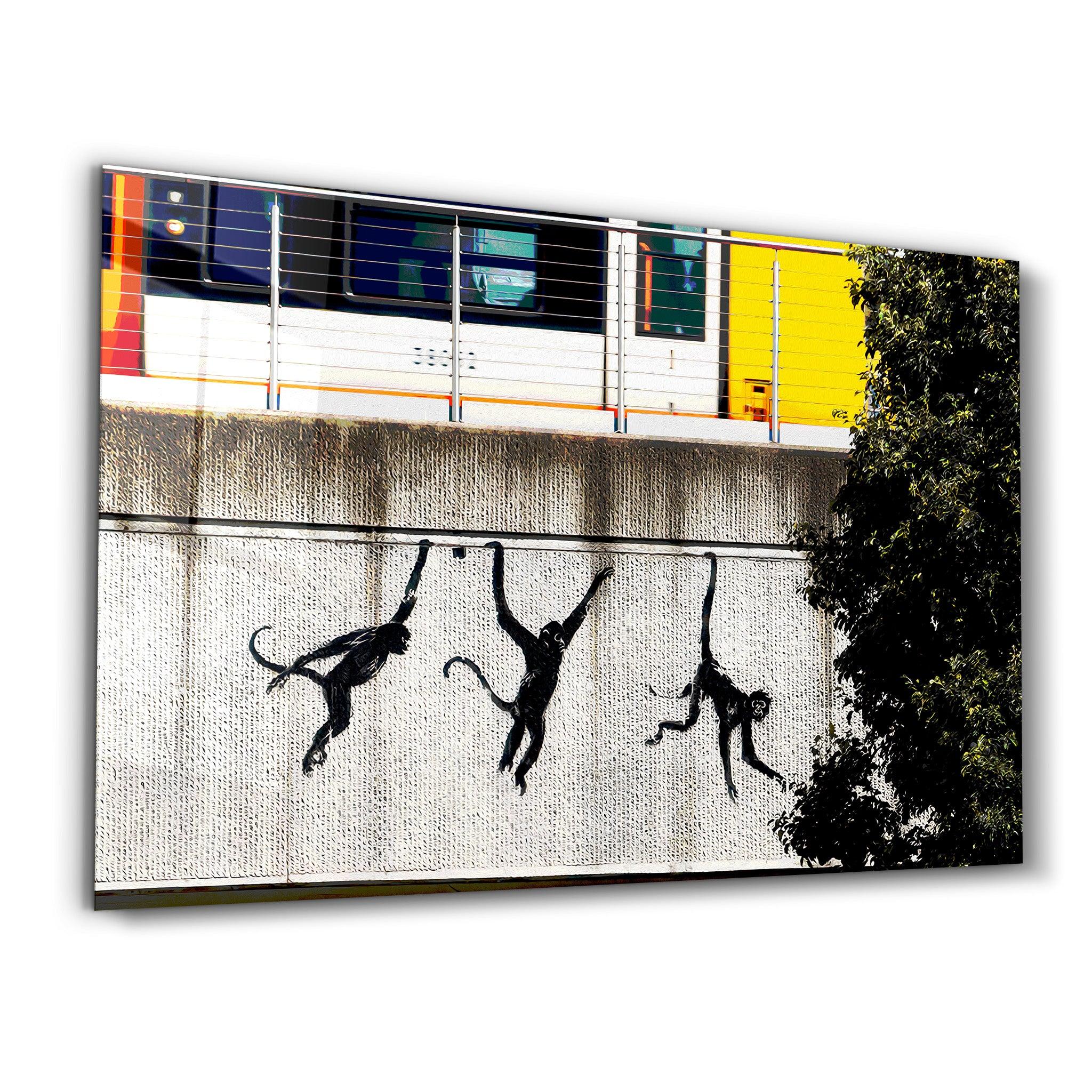 Banksy Monkeys on the Train Bridge glass wall art by Artdesigna showing a graffiti scene on clear glass surface.